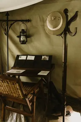 a room with a desk with a clock and a lamp at Serengeti Pioneer Camp in Mugumu