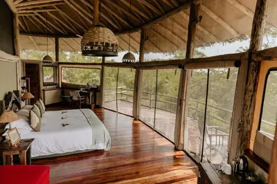 a bedroom with a bed in a room with windows at Tarangire Treetops in Monduli