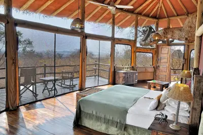 a bedroom with a bed in a room with a balcony at Tarangire Treetops in Monduli