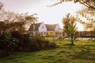 a large white house with a yard with trees at Kili Seasons Hotel in Arusha