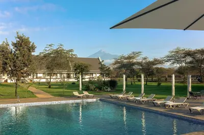 a swimming pool with lounge chairs and a building at Kili Seasons Hotel in Arusha