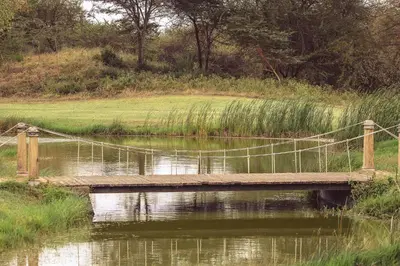 a wooden bridge over a body of water at Kili Seasons Hotel in Arusha