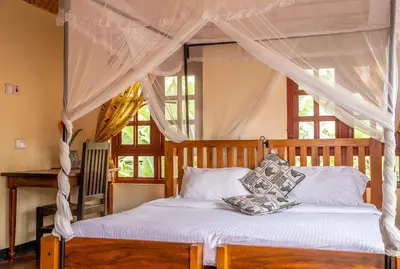 a bedroom with a canopy bed with white sheets and pillows at Christina House in Arusha
