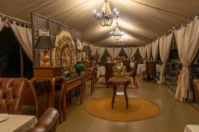 a dining room with tables and chairs and a chandelier at TARANGIRE KURO TREETOP LODGE in Manyara