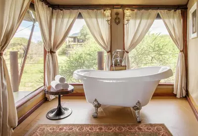 a bathroom with a tub in front of a window at TARANGIRE KURO TREETOP LODGE in Manyara