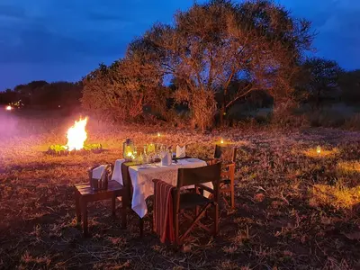 a dinner table with a fire in a field at TARANGIRE KURO TREETOP LODGE in Manyara