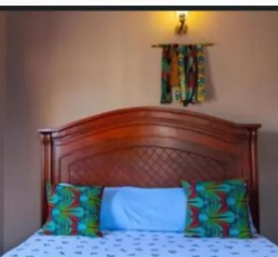 a bed with a wooden head board and two pillows at Zimbe Host Arusha in Arusha
