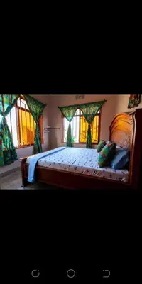 a bedroom with a large bed with windows at Zimbe Host Arusha in Arusha