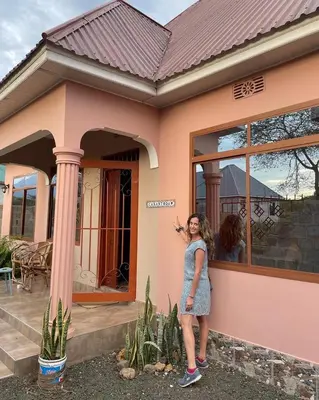 a woman standing in front of a house at Zimbe Host Arusha in Arusha