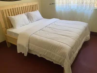 a large bed with white sheets and pillows at Manyada Inn in Arusha