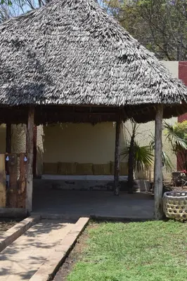 a straw roofed pavilion with a bench in a yard at Stasumo House Arusha in Arusha