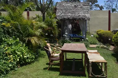a table and chairs in a garden with a small table at Stasumo House Arusha in Arusha