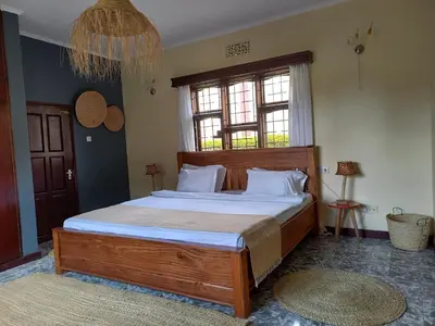 a bedroom with a large wooden bed with white pillows at Stasumo House Arusha in Arusha