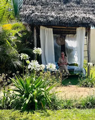 a man sitting in the window of a hut at Stasumo House Arusha in Arusha