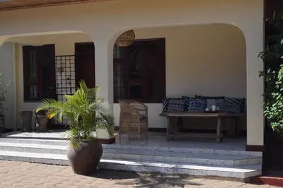 a porch of a house with a table and chairs at Stasumo House Arusha in Arusha
