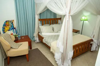 a bedroom with a canopy bed and a chair at Blue elephant villas in Arusha