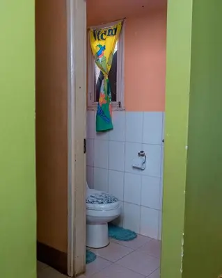 a bathroom with a toilet and a window with a curtain at FARAJA HOMESTAY- Seamless Comfort in the Heart of the City - Free WiFi, Warm Hospitality, and Local Delights Await in Moshi