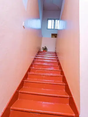 a staircase in an empty room with orange walls at FARAJA HOMESTAY- Seamless Comfort in the Heart of the City - Free WiFi, Warm Hospitality, and Local Delights Await in Moshi