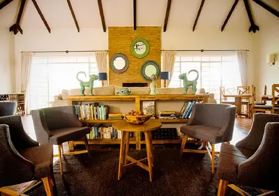 a living room with a table and chairs and a clock at Katambuga House in Arusha