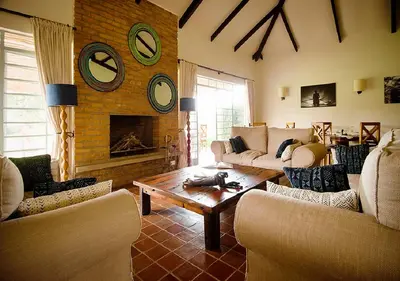 a living room with couches and a table and a fireplace at Katambuga House in Arusha