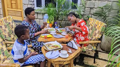 a group of people sitting around a table eating food at Kilimanjaro Scenic Homestay in Moshi