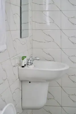 a white bathroom with a sink and a mirror at Sarita Village Homes in Arusha