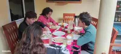 a group of people sitting around a table with a baby at Kisanga Homestay in Moshi