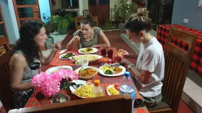 a group of people sitting at a table eating food at Kisanga Homestay in Moshi