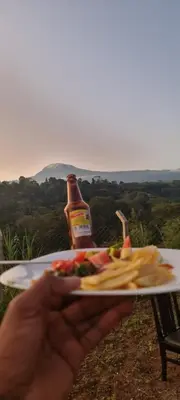 a person holding a plate of food and a bottle of beer at Kisanga Homestay in Moshi
