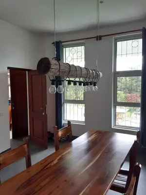a dining room with a wooden table and some windows at Themi View in Arusha