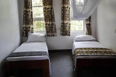 two beds in a room with two windows at Themi View in Arusha