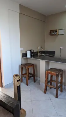 a kitchen with a counter and a sink and two stools at Mufasa city Apartments in Arusha