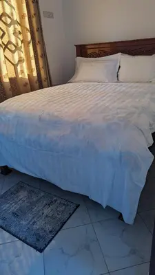 a bedroom with a large bed with a white comforter at Mufasa city Apartments in Arusha