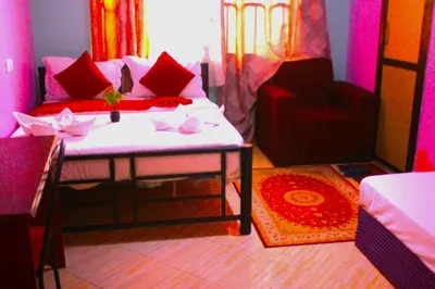 a room with a bed and a couch and a chair at Safari Park House in Arusha