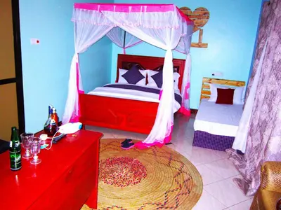 a bedroom with a canopy bed and a red dresser at Safari Park House in Arusha