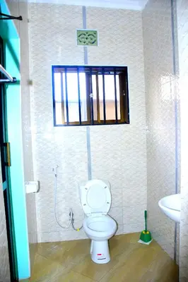 a bathroom with a toilet and a sink and a window at Safari Park House in Arusha