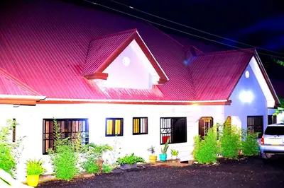 a large white house with a red roof at Safari Park House in Arusha