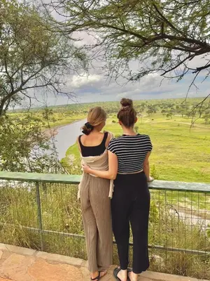 two women standing on a fence looking at a river at Tiny house with amazing view in Arusha