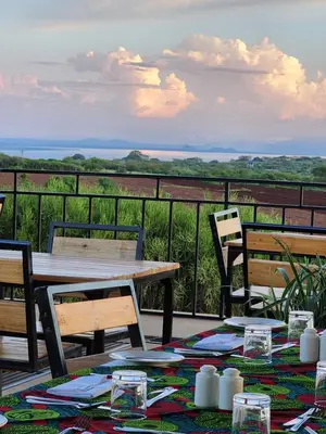a table and chairs on a balcony with a view at Heart and Soul Lodge in Karatu