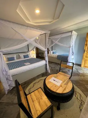 a bedroom with two beds and a table and a table sidx sidx sidx at Heart and Soul Lodge in Karatu