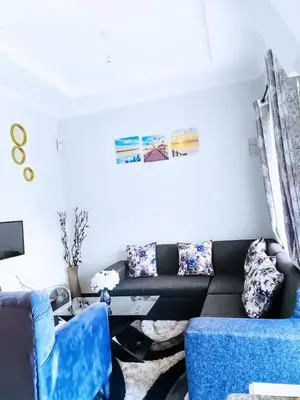 a living room with a black couch and blue chairs at eneyahomes ~ stay with me in Arusha