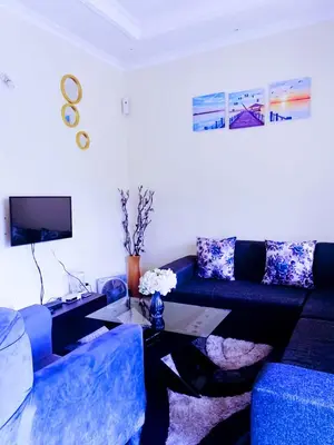 a living room with a blue couch and a table at eneyahomes ~ stay with me in Arusha