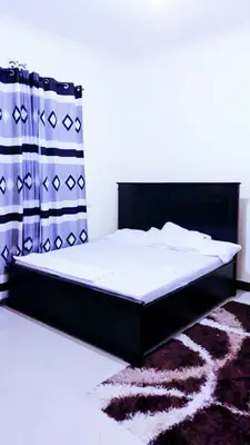 a bed in a bedroom with a black bed frame at eneyahomes ~ stay with me in Arusha