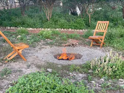 a fire pit with a bench and a chair at Mwi Village House in Mto wa Mbu