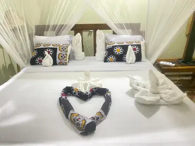 a bed with two swans and a bow tie on it at Mwi Village House in Mto wa Mbu