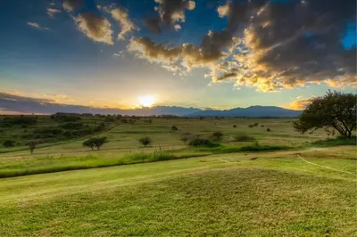 a field with the sun setting in the horizon at Africa Safari Karatu in Karatu