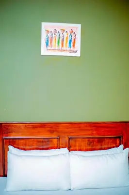a bedroom with a wooden headboard and a green wall at Kiteme Comfort Lodge in Arusha
