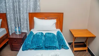 a bedroom with a bed with a wooden headboard and a table at Kiteme Comfort Lodge in Arusha