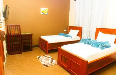 a bedroom with two beds and a night stand at Kiteme Comfort Lodge in Arusha