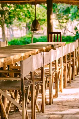 a row of wooden tables with white chairs at The Jungle Pearl Resort in Mto wa Mbu